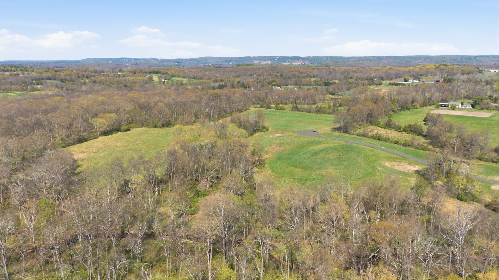 Springtime aerial of open fields, the private roadway and surrounding woodland at 1310 Lamington Road, Bedminster